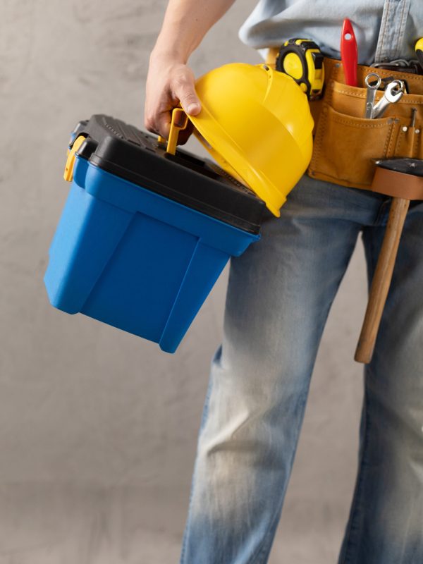 Man worker holding construction helmet and toolbox near wall. Male hand and construction tools. Renovation or repair concept
